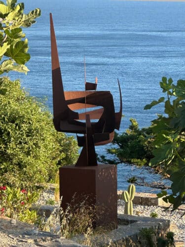 Œuvre d'art MPCEM en acier Corten intégrée dans le paysage sauvage méditerranéen en Crête